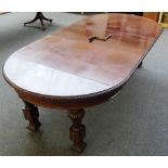 An early 20th century circular mahogany extending dining table on fluted supports and knurl feet