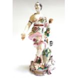 A Bow figure of a classical maiden, circa 1760, standing with one arm resting on a tree stump,