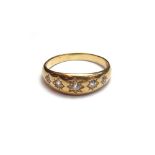 A gold and diamond set five stone ring, star gypsy set with a row of cushion shaped diamonds,