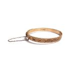 A 9ct gold oval hinged bangle, with star cut and textured decoration, on a snap clasp,