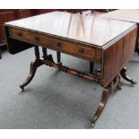 An early 19th century brass inlaid rosewood sofa table on four reeded columns and four downswept