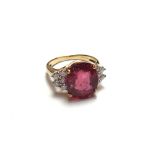 An 18ct gold, ruby and diamond set ring, claw set with the oval cut ruby at the centre,