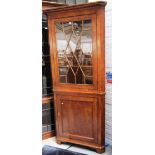 A George III oak double height corner display cabinet cupboard on bracket feet,