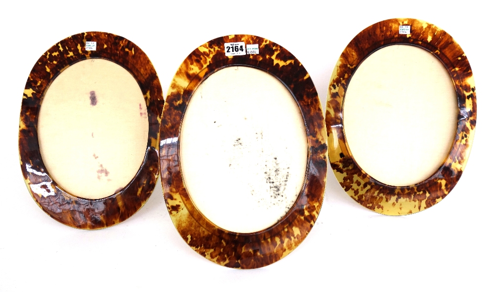 Three faux tortoiseshell oval strut back photograph frames, 35cm high (3).