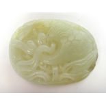 A Chinese jade oval plaque, carved and pierced with a crane in flight amongst lotus,