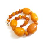 A single row necklace of vary sized amber and reconstituted amber beads,