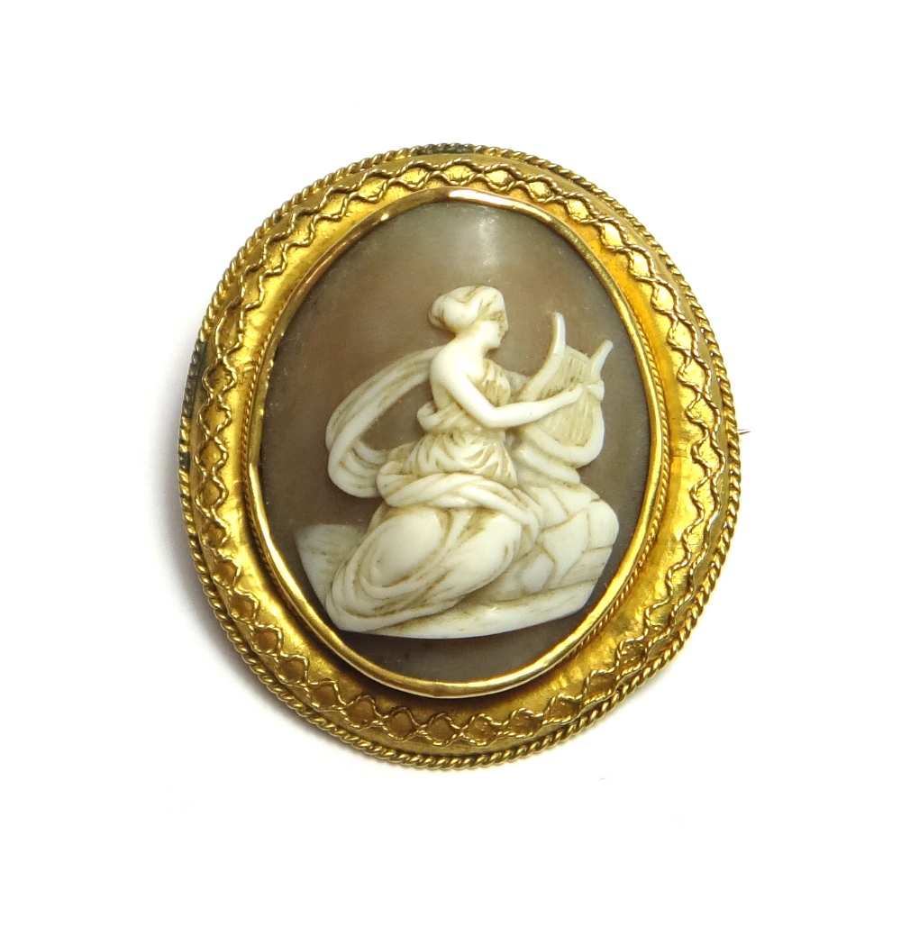 A Victorian oval shell cameo brooch, carved as the figure of a classical lady playing a lyre,