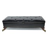 A large rectangular black leather upholstered lift top footstool on gilt metal capped carved