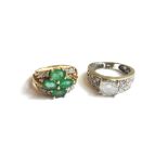 A 9ct gold, emerald and diamond set ring, claw set with four oval cut emeralds,