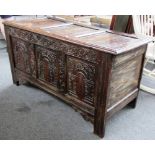 A 17th century oak coffer, the three panel lid over a carved triple panel front on stile feet,