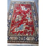 A Ghom part silk rug, Persian, the madder field with a hunting scene with horseman and riders,