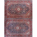 A pair of Kashan rugs, Persian, each with a dark indigo field, a sage and madder medallion,