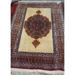An Indian rug, the plain ivory field with a bold rosette medallion in salmon pink and red,
