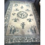 A Chinese carpet the ivory field with a fret roundel, vases and  sprays,