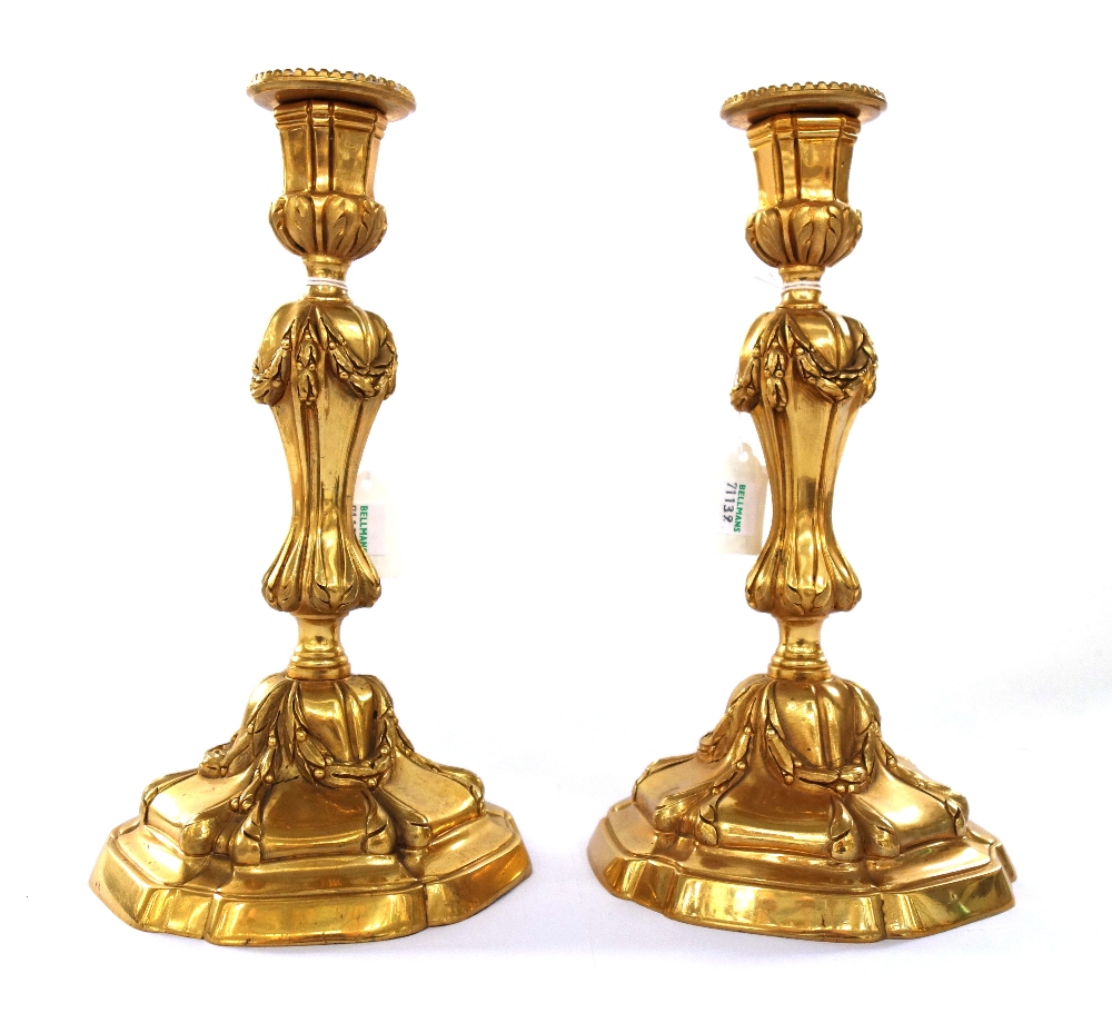 A pair of Georgian style gilt bronze candlesticks, modern, with foliate cast decoration,
