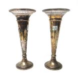 A pair of silver trumpet shaped vases, each with a pierced flared rim and on a loaded circular base,