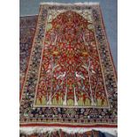 An Indian prayer rug, the madder mihrab with a flowering plant design,