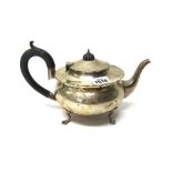 A silver teapot, of circular form, raised on three feet and having black fittings, London 1918,