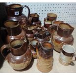 A quantity of brown glazed Royal Doulton items including jugs, tankards, mustard pot and sundry.