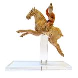 A Tang style pottery female polo player, seated astride a galloping horse, wearing a red tunic,