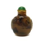 A chalcedony snuff bottle, 19th/20th, with dark brown inclusions, carved with mask and ring handles,