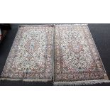 A pair of Indian silk rugs, the ivory fields each with a pink medallion,