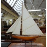 A vintage wooden pond yacht, 'Eileen', with stained wooden hull and lead keel, on a mahogany base,