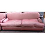 A large 20th century sofa of Howard design on three turned front supports resting on brass caps and