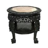 An early 20th century Chinese profusely carved two tier urn stand, with shaped inset marble top,