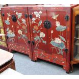 A pair of 20th century Chinese red lacquer and polychrome painted two door low cupboards,