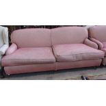 A large 20th century sofa of Howard design on three turned front supports resting on brass caps and