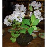 A pair of green pottery plant pots with artificial flowers.