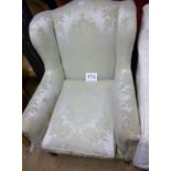 An early 20c winged armchair in cream si