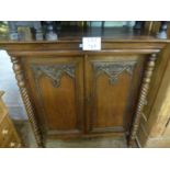 A 19c mahogany and teak cupboard with double carved doors flanked either side by spiral twist