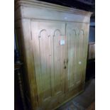 A large Victorian pine double wardrobe with two double arched panelled doors and drawer beneath