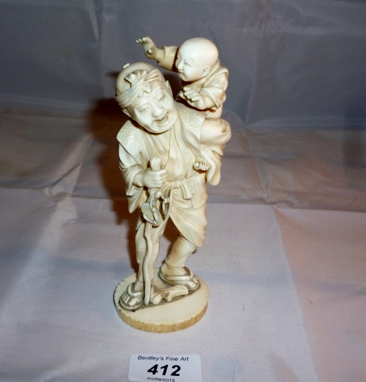 An oriental ivory carving of an old man carrying a child signed est: £120-£160
