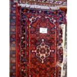 A 20c wool rug on red ground (130 x 70 cm approx) est: £30-£40