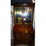 An 18c walnut bureau bookcase with double mirrored doors over a fitted bureau interior and drawers