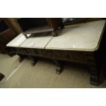 A Flemish low dresser with three marble top panels over three carved drawers and four carved feet