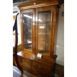 An Edwardian mahogany bookcase with double glass doors over two short and two long drawers est: