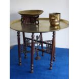 Large 68.5cm circular brass tray decorated with figures and animals on a folding six leg table base,