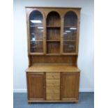 A Ducal style light oak display dresser with domed twin glazed doors,