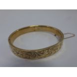 9ct gold hinged bangle with engraved foliate decoration and safety chain, 12.