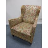 A 19th Century wing back armchair with gold floral upholstery, on turned front supports and castors,