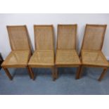 A set of four light oak chairs with caned backs and seats