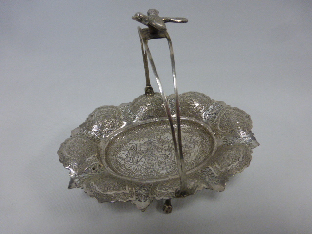 A Middle Eastern silver swing handled dish with bird finial,