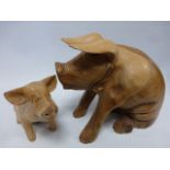 Two carved wooden models of seated pigs,