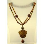 AN AGATE CARVED BUTTERFLY of mushroom colour, on an agate bead necklace of large and small beads,