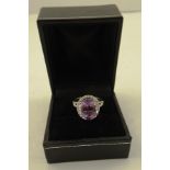 A RHODIUM FINISHED WHITE GOLD COLOURED METAL DRESS RING set with central amethyst and diamonds
