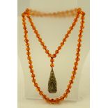 AN AMBER NECKLET of uniform beads and carved Nephrite figure pendant, portraying a penitent